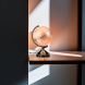 Globe-shaped lamp on a shelf next to a wall, with soft ambient lighting