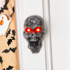 Skelet deurbel naast de deur met Halloween decoraties