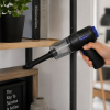 Mannsberger handstofzuiger reinigt een houten kastplank in huis.