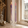 Rainbow drip kaarsen in glazen kandelaars bij het raam met warme decoratieve setting