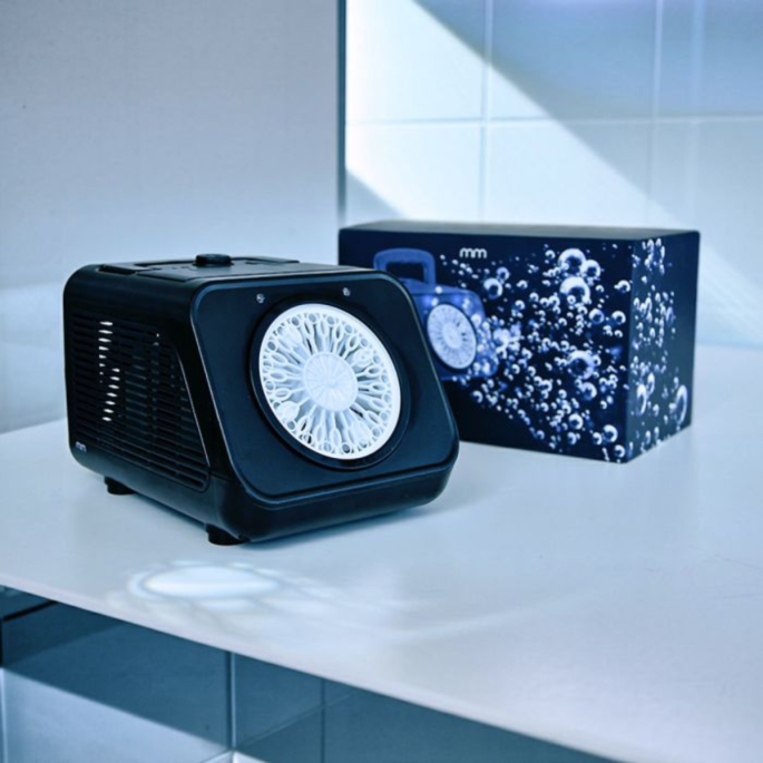 Zwarte bellenblaasmachine op een tafel, met productverpakking op de achtergrond.