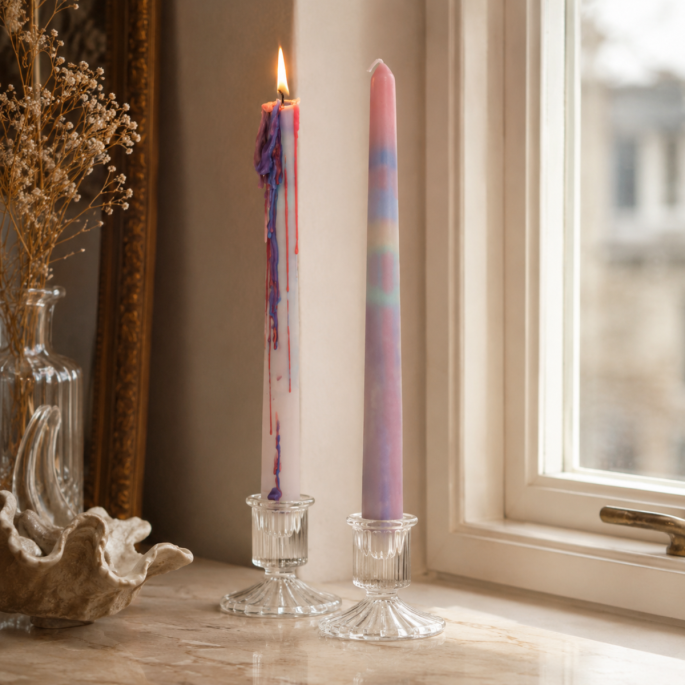 Rainbow drip kaarsen in glazen kandelaars bij het raam met warme decoratieve setting