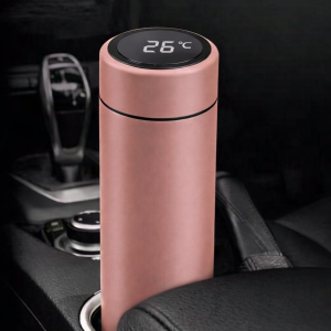 Roze thermosfles met digitale temperatuurmeter geplaatst in de bekerhouder van een auto.