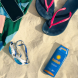 SunSafe zonnebrand verstopkluis op strand naast slippers, telefoon en zwembril